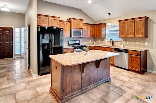 kitchen with a kitchen bar, sink, hanging light fixtures, appliances with stainless steel finishes, and a kitchen island