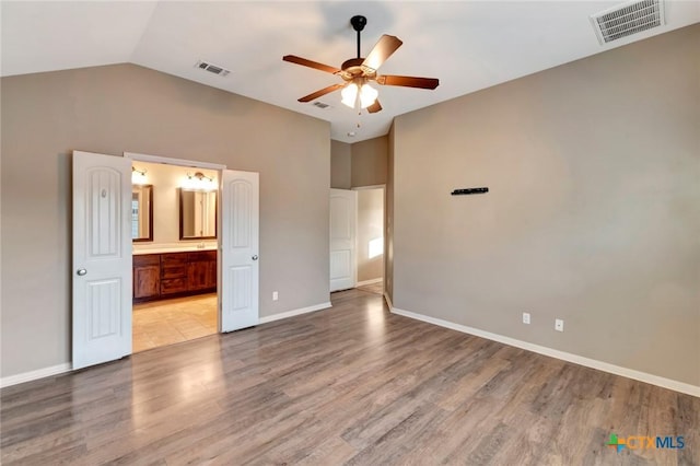 unfurnished bedroom with lofted ceiling, connected bathroom, light hardwood / wood-style floors, and ceiling fan