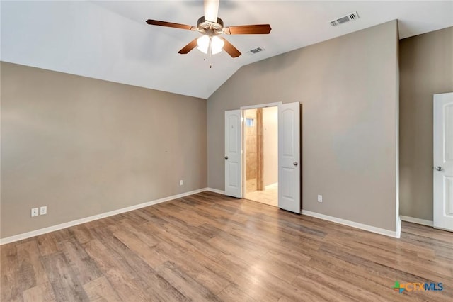 unfurnished bedroom featuring lofted ceiling, light hardwood / wood-style floors, ceiling fan, and ensuite bathroom