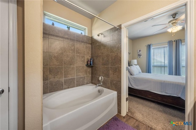 bathroom with washtub / shower combination, ensuite bathroom, wood finished floors, and a ceiling fan