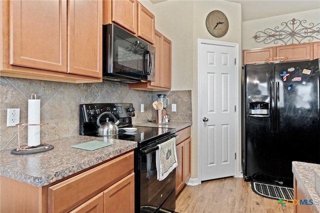 kitchen with light wood finished floors, light countertops, backsplash, and black appliances