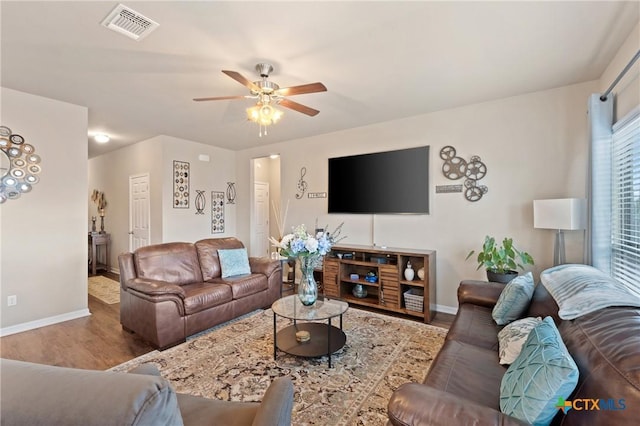 living room featuring wood finished floors, visible vents, a ceiling fan, and baseboards