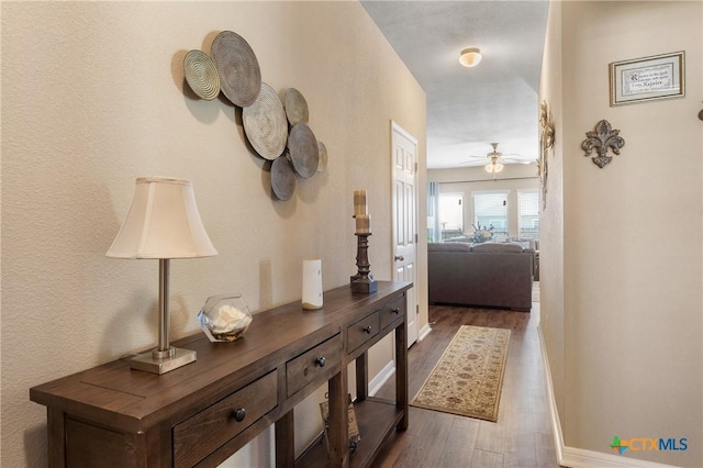 corridor with baseboards and dark wood-style floors