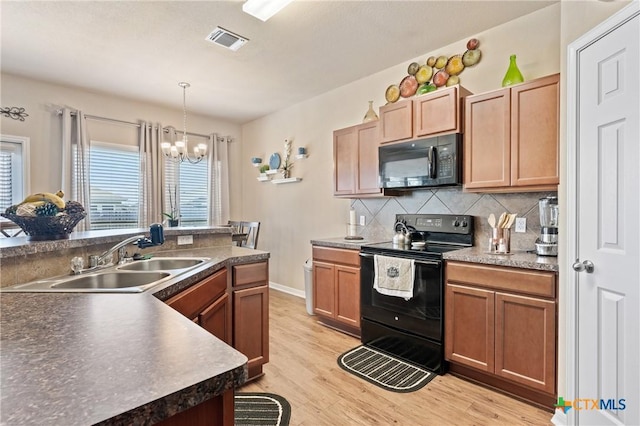 kitchen with light wood finished floors, a sink, tasteful backsplash, visible vents, and black appliances