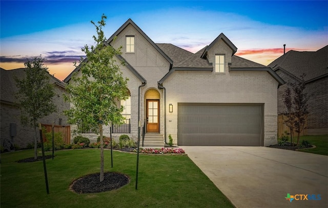 367 Five Mile Creek Way, Kyle, TX 78640 - french country inspired facade featuring concrete driveway, a front yard, a garage, a shingled roof, and brick siding