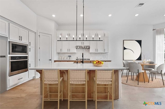 367 Five Mile Creek Way, Kyle, TX 78640 - kitchen with appliances with stainless steel finishes, light countertops, decorative backsplash, light wood finished floors, and recessed lighting