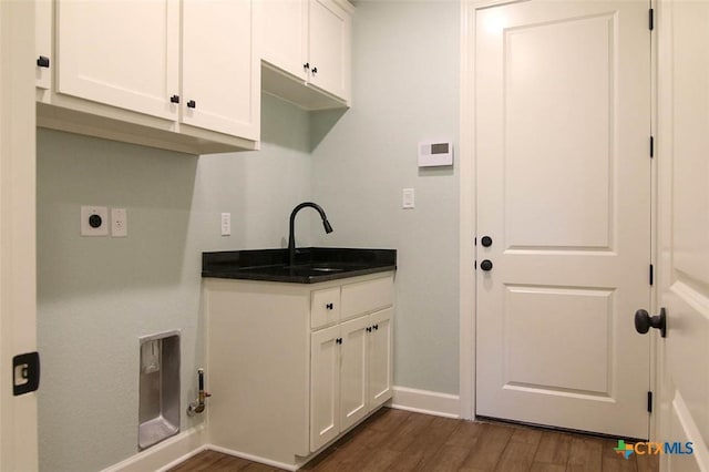 laundry area with electric dryer hookup, sink, dark hardwood / wood-style floors, and cabinets