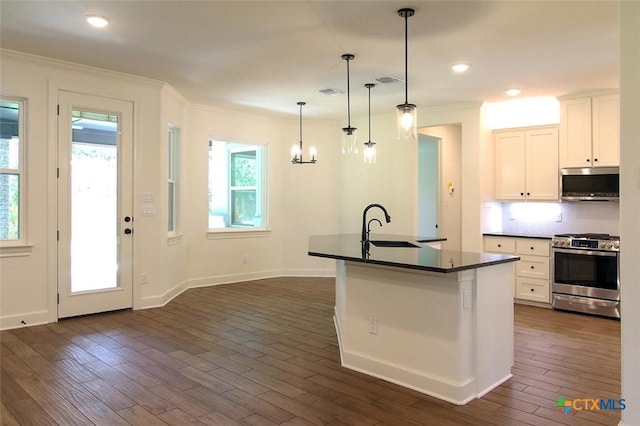 kitchen with appliances with stainless steel finishes, pendant lighting, white cabinetry, an island with sink, and sink