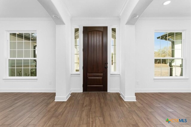 unfurnished dining area featuring wood-type flooring, a chandelier, and crown molding