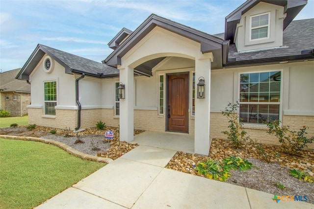 4113 Turning Leaf Dr, Nolanville, TX 76559 - doorway to property with stucco siding, brick siding, and roof with shingles
