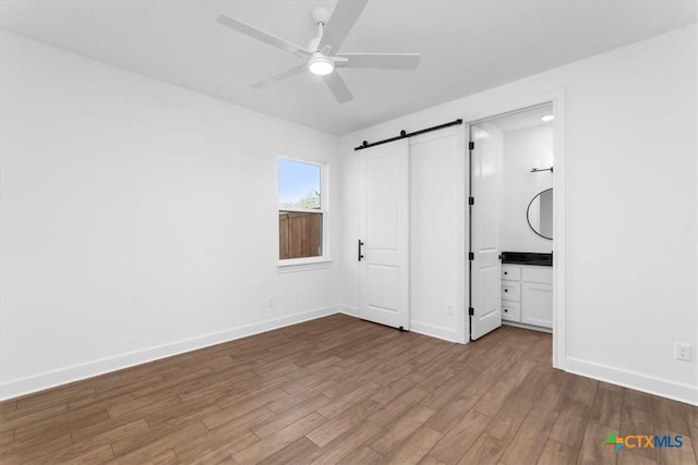 4113 Turning Leaf Dr, Nolanville, TX 76559 - unfurnished bedroom featuring a barn door, wood finished floors, baseboards, and a ceiling fan