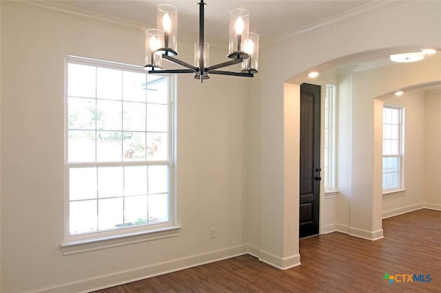 unfurnished dining area with dark hardwood / wood-style flooring, a notable chandelier, a wealth of natural light, and ornamental molding