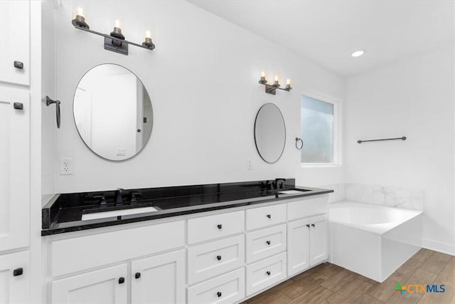 bathroom with vanity, wood-type flooring, and a tub