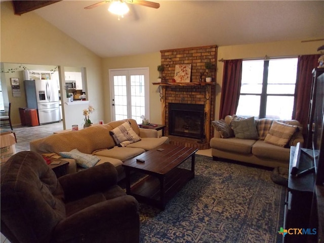 living room featuring vaulted ceiling with beams, a brick fireplace, and ceiling fan