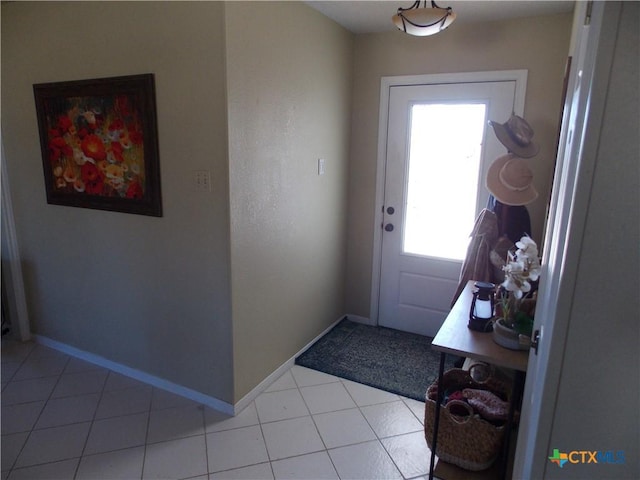 doorway to outside featuring baseboards and light tile patterned flooring