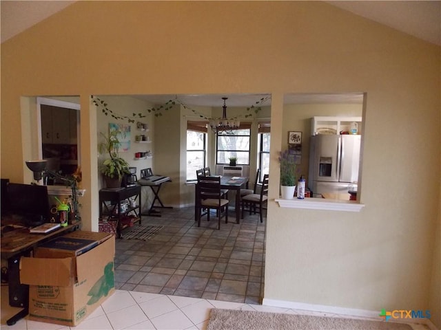 dining room featuring tile patterned flooring, lofted ceiling, and a notable chandelier