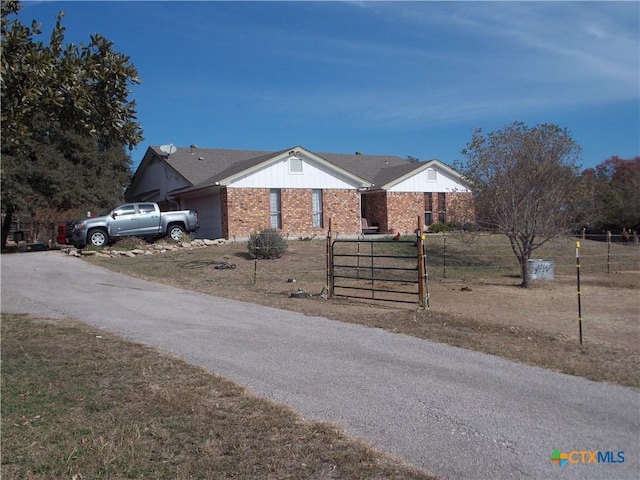 view of front of home with brick siding, an attached garage, and fence private yard
