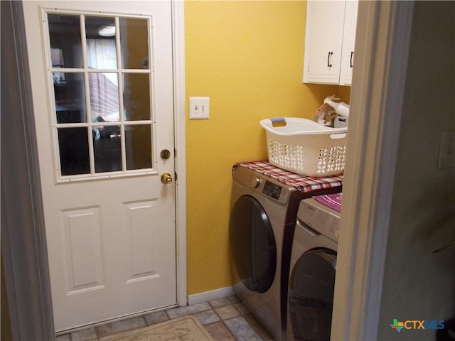 clothes washing area with cabinets and separate washer and dryer