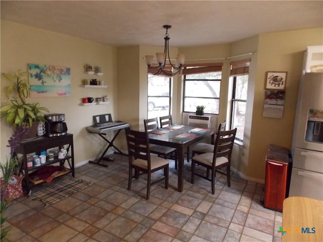 dining area with baseboards, an inviting chandelier, and stone finish floor