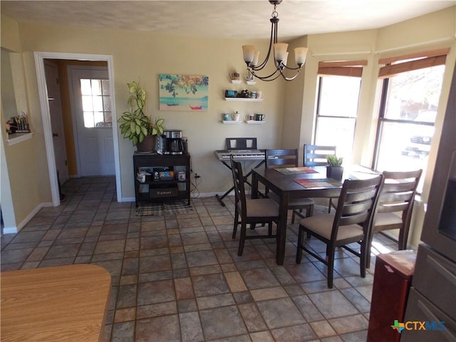 dining room featuring baseboards, a notable chandelier, and stone finish floor