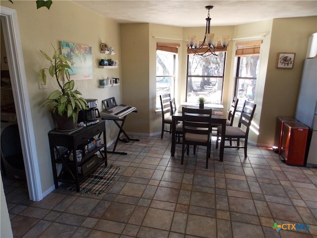 dining space with baseboards, a chandelier, plenty of natural light, and stone finish floor