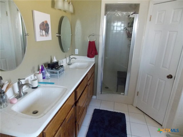 bathroom featuring double vanity, a shower stall, a sink, and tile patterned flooring