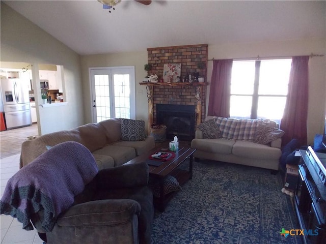 living room with tile patterned flooring, ceiling fan, a brick fireplace, and lofted ceiling