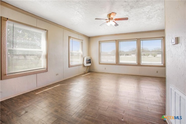 704 Maple St, Yoakum, TX 77995 - unfurnished room featuring ceiling fan, a textured ceiling, ornamental molding, heating unit, and wood finished floors