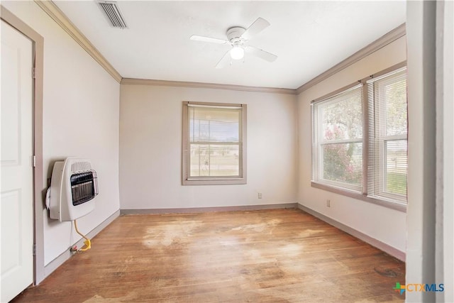 704 Maple St, Yoakum, TX 77995 - unfurnished room featuring ornamental molding, healthy amount of natural light, heating unit, ceiling fan, and light wood-style flooring