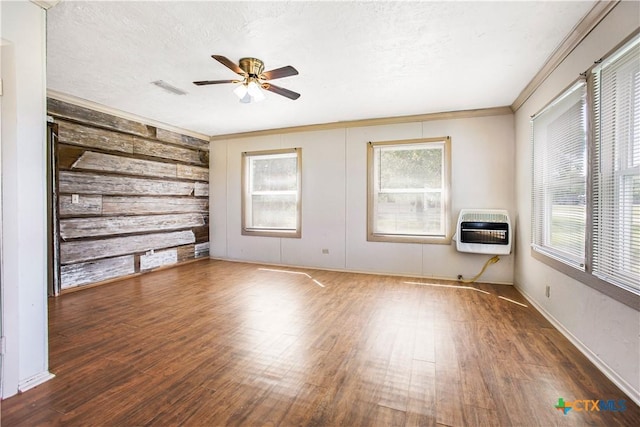 704 Maple St, Yoakum, TX 77995 - empty room with heating unit, wood finished floors, a ceiling fan, and wood walls