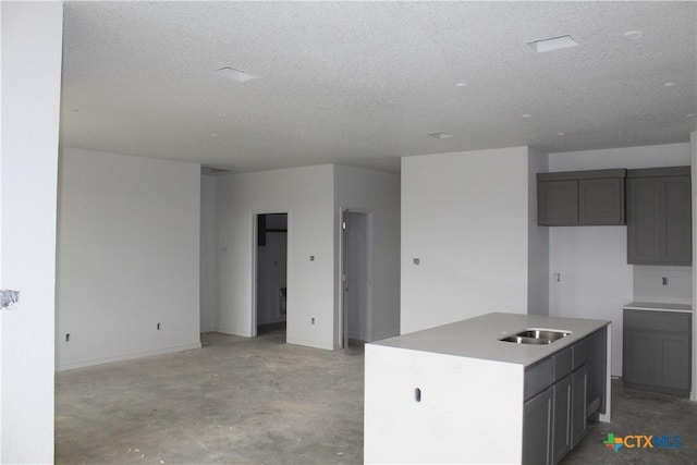 kitchen with gray cabinets, sink, a kitchen island, and a textured ceiling