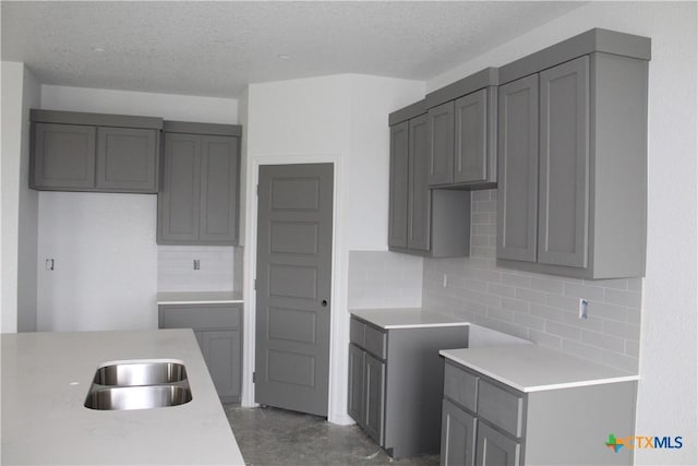 kitchen featuring a textured ceiling, backsplash, and sink