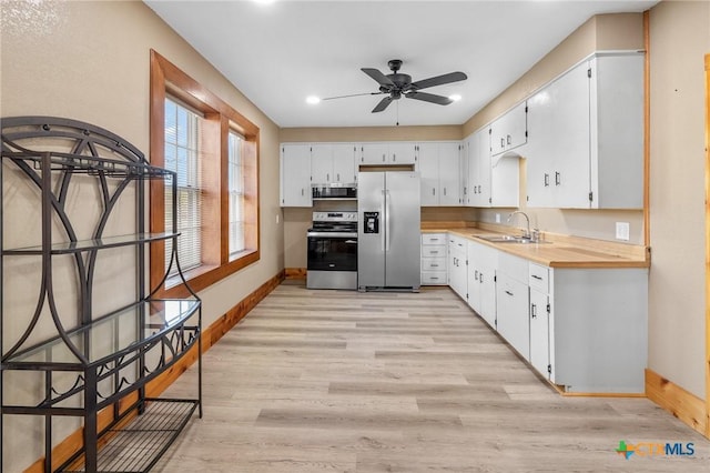 kitchen featuring white cabinets, sink, ceiling fan, light wood-type flooring, and appliances with stainless steel finishes