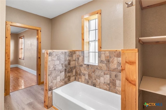 bathroom with a tub to relax in, hardwood / wood-style floors, and tile walls