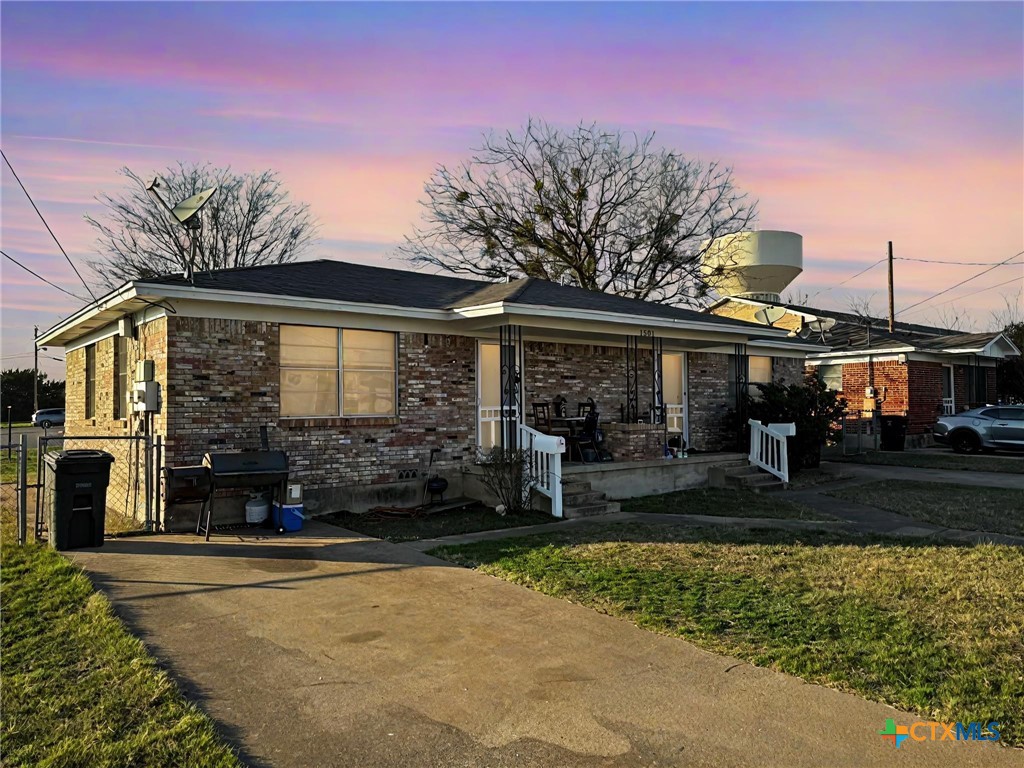 view of front of house with covered porch, brick siding, and a front lawn