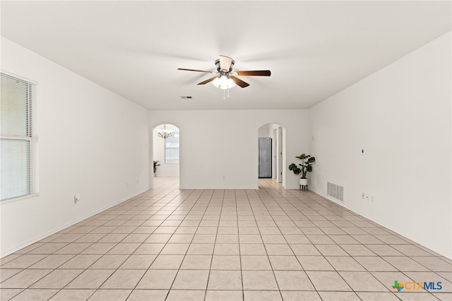 3908 Fieldcrest Dr, Killeen, TX 76549 - empty room featuring arched walkways, a ceiling fan, a chandelier, and light tile patterned floors
