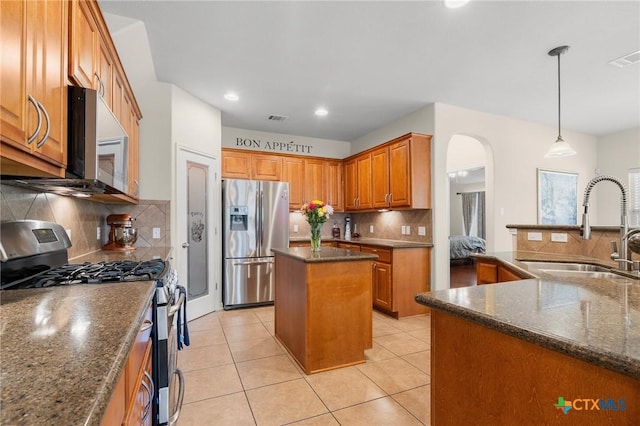 101 Payne Stewart Dr, Round Rock, TX 78664 - kitchen featuring stainless steel appliances, a center island, decorative backsplash, arched walkways, and light tile patterned floors