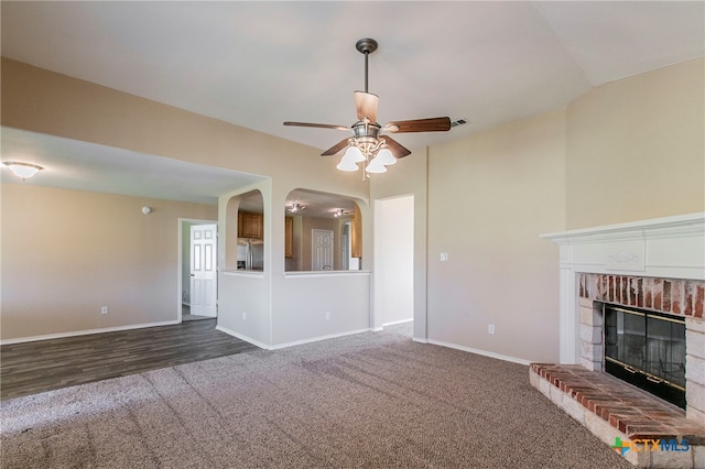 unfurnished living room featuring a fireplace, dark hardwood / wood-style floors, and ceiling fan