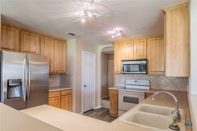 kitchen with sink, decorative backsplash, appliances with stainless steel finishes, light brown cabinetry, and dark hardwood / wood-style flooring