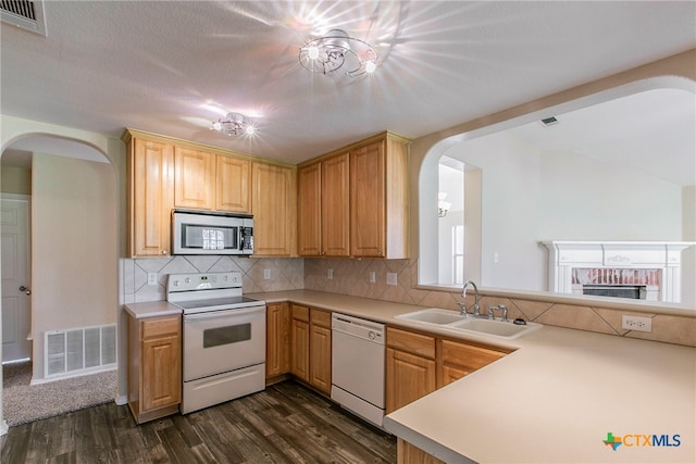 kitchen with backsplash, a textured ceiling, dark hardwood / wood-style floors, sink, and white appliances