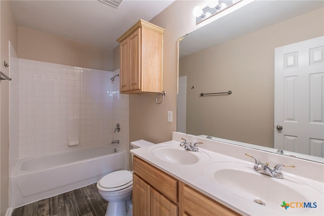 full bathroom with hardwood / wood-style flooring, vanity, toilet, and tiled shower / bath combo