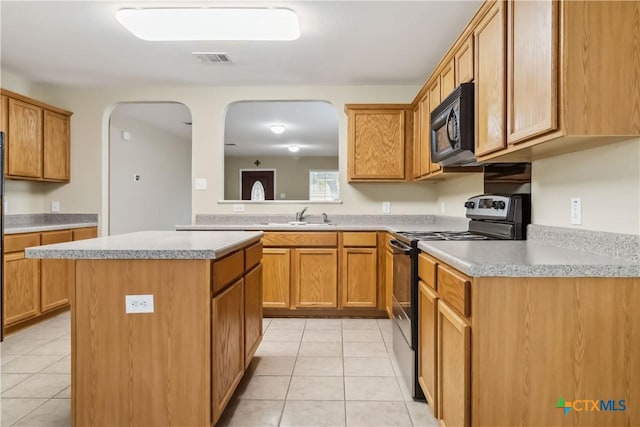 kitchen featuring light tile patterned floors, black appliances, visible vents, a kitchen island, and arched walkways