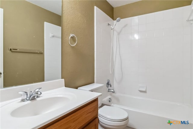 bathroom with vanity, toilet, a textured wall, and bathtub / shower combination