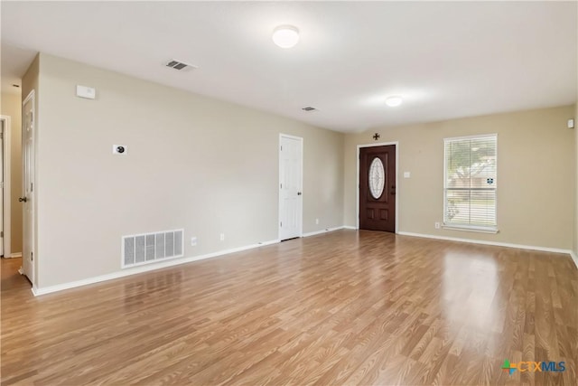 unfurnished living room featuring baseboards, visible vents, and light wood-type flooring