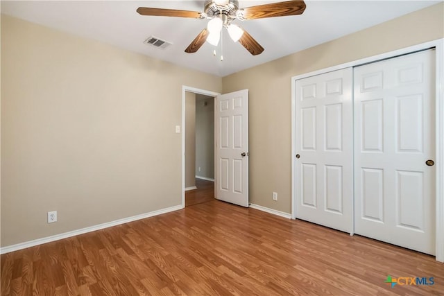 unfurnished bedroom featuring light wood-style floors, a closet, ceiling fan, visible vents, and baseboards