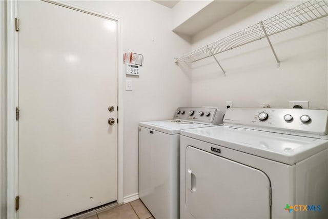 washroom featuring light tile patterned flooring, separate washer and dryer, and laundry area