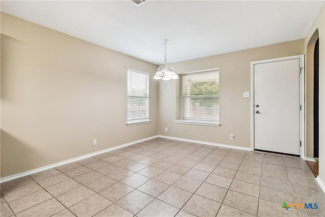 unfurnished dining area featuring light tile patterned floors, arched walkways, a notable chandelier, and baseboards