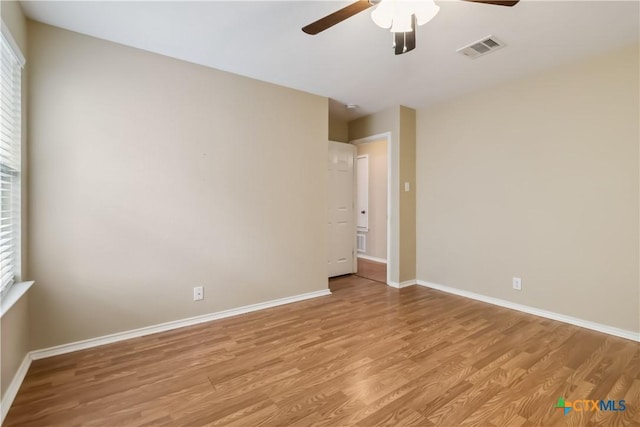 unfurnished room with baseboards, visible vents, ceiling fan, and light wood-style flooring