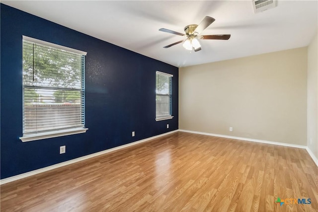spare room with visible vents, ceiling fan, wood finished floors, and baseboards