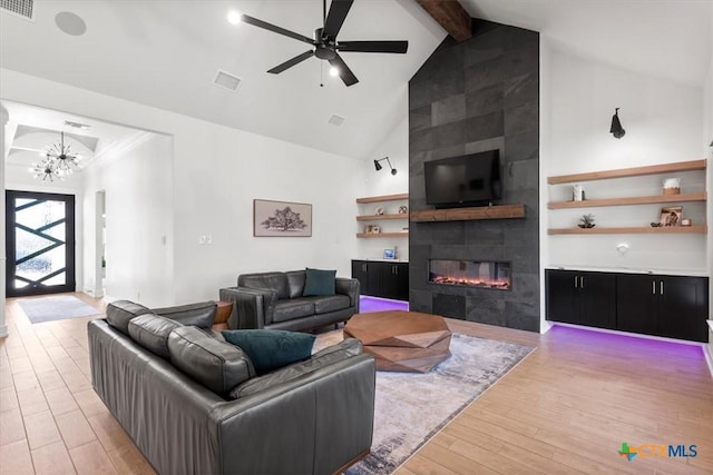 813 Eagle Heights Dr, Salado, TX 76571 - living room featuring light wood-type flooring, a tiled fireplace, beam ceiling, high vaulted ceiling, and a chandelier